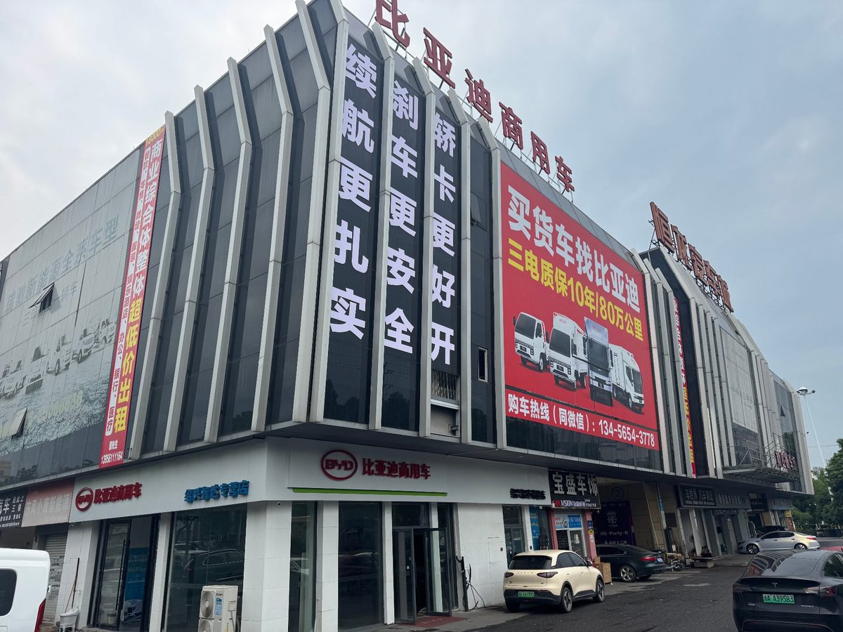 客户场地实景：展销中心主楼幕墙与一层展厅入口，门前停放展车