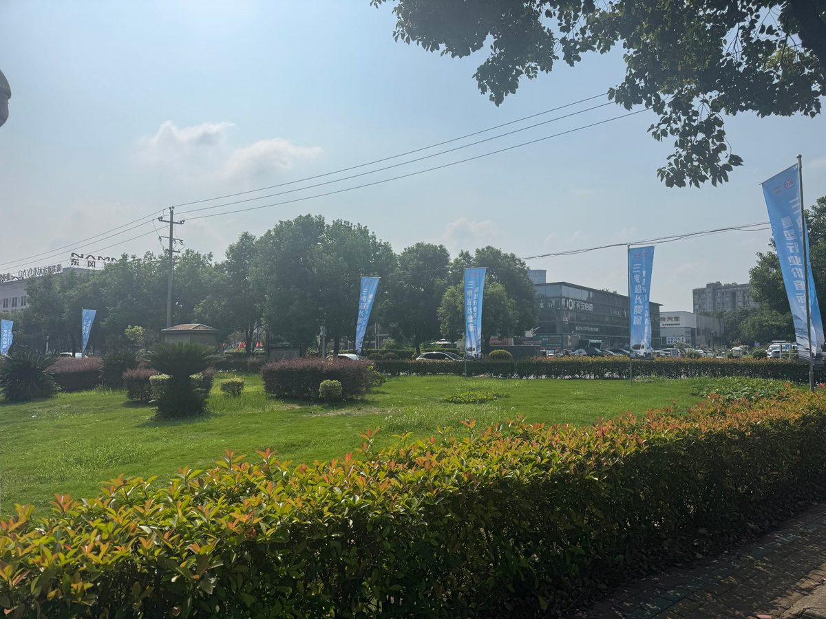 客户场地实景：园区绿化带与客户到店通道，沿路设置品牌道旗